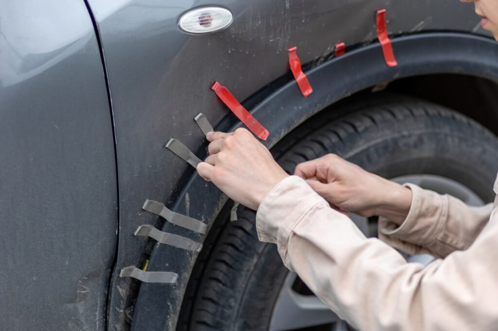 a man glues a car wing that has fallen off after an accident on tape