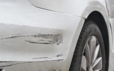 Car with paint scratches parked in rainy weather