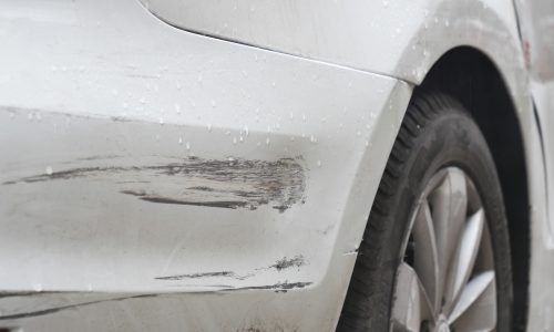 Car with paint scratches parked in rainy weather