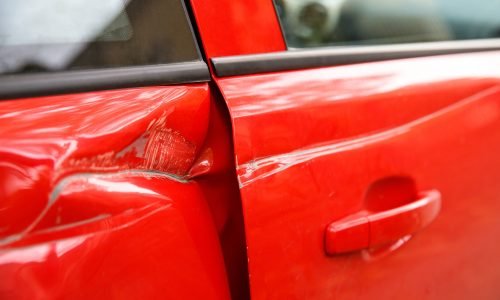 Door red car damaged in a deep dent accident, scratches on the doors. Car repair concept.