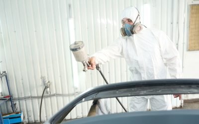 Skilled auto repair shop worker is painting motor vehicle body panel